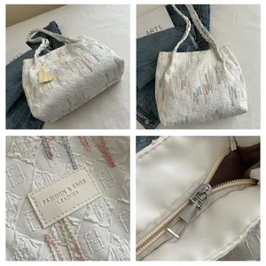 Dettagli della borsa tote trapuntata bianca con ricamo arcobaleno e accenti nappe