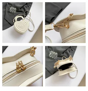 Macro detail of creamy heart-shaped bag showing gold hardware and smooth zipper stitching