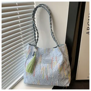Dettaglio della borsa jacquard azzurra con ricami colorati e nappa con frange verdi