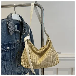 Close-up of handwoven straw tote with adjustable white leather knot strap and natural texture