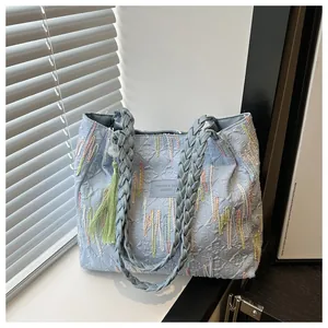 Dettaglio borsa tote trapuntata azzurra con manici intrecciati e ricami colorati