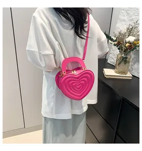Detail of pink heart-shaped bag with quilted texture and golden double zipper closure