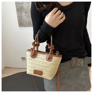Detail der Strohtasche mit braunen Ledergriffen und verstellbarem Schultergurt