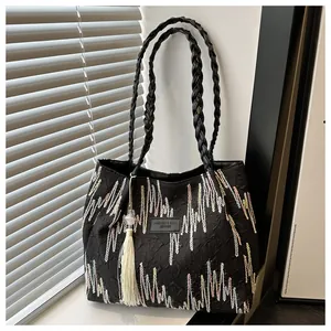 Dettaglio borsa tote nera con ricami floreali e manici in pelle intrecciata