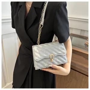 Detail of silver quilted handbag with golden twist lock and chain strap on a black dress