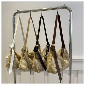 Detail of hand-woven straw tote bags with colorful leather straps on a metal rack