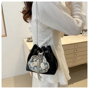 Détail de broderie florale sur sac seau en velours noir avec bandoulière chaîne