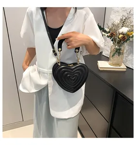 Detail of heart-shaped crossbody bag with quilted patterns and gold metal hardware