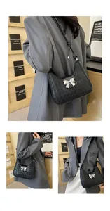 Detail of black woven shoulder bag featuring a silver bow buckle and knotted strap