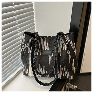 Dettaglio della borsa tote nera trapuntata con ricami colorati e targhetta in pelle