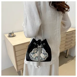 Détail de broderie florale sur sac seau en velours noir avec chaîne et pampille perle