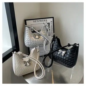 Detailed view of woven shoulder bags with metallic bow buckles in silver, cream and black