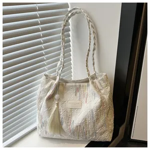 Dettaglio della borsa tote crema con texture a rilievo e tracolla in tessuto chic