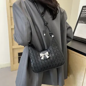Minimalist black woven leather crescent shoulder bag with a silver bow buckle detail