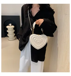 Close-up of heart-shaped quilted handbag with golden chain handle and white strap