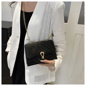 Quilted black crossbody bag with gold hardware worn by a model in a white blazer