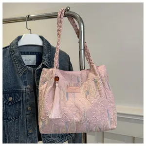 Dettaglio della borsa tote rosa trapuntata con ricami e tracolla intrecciata a mano