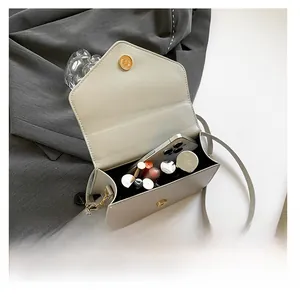 Detail showing inner storage capacity of the beige envelope bag with phone and lipsticks