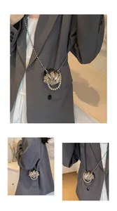 Dettaglio mini borsa a conchiglia argento con tracolla in perline su blazer grigio