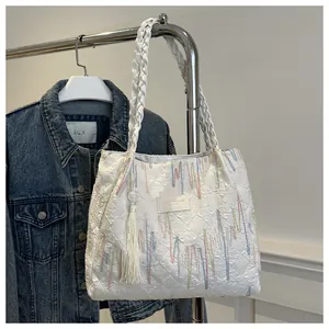 Dettaglio della borsa tote bianca con ricami multicolore e ciondolo a nappa decorativo