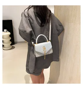 Detail showing the light blue sequin texture and golden SS logo with tassel on the bag
