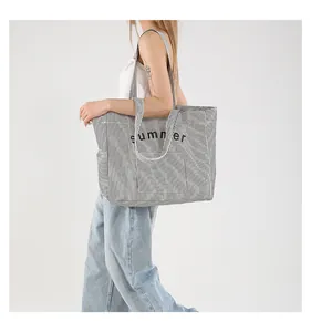 Detailed view of striped canvas tote bag with summer print on female model shoulder