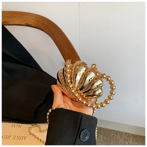 Dettaglio della clutch dorata a forma di conchiglia con manico di perle e texture
