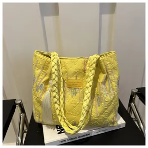 Dettaglio ravvicinato della borsa tote gialla con trama monogram e applicazione in pelle