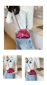 Detail of metallic rose red pleated cloud bag with slim matching crossbody strap