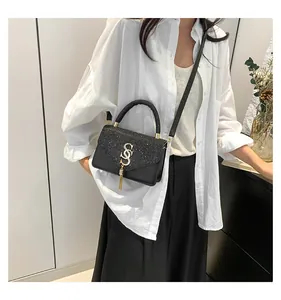 Detail of black PU leather crossbody bag with sequin flap, golden S buckle and long tassel