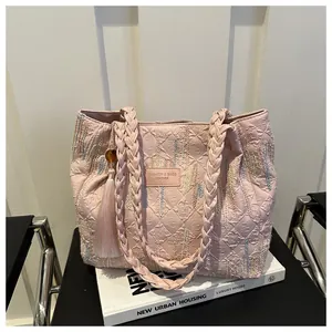 Dettaglio della borsa tote rosa trapuntata con ricami floreali e manici intrecciati