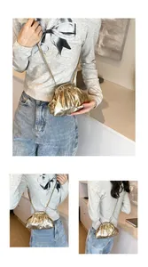 Detail view of gold pleated cloud bag showing metallic finish and slim shoulder strap