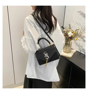 Detail of crossbody bag with star-glitter flap, gold SS logo and elegant long tassel