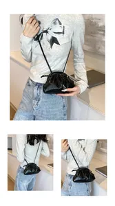 Detail of black ruched dumpling bag with glossy finish and slim shoulder strap