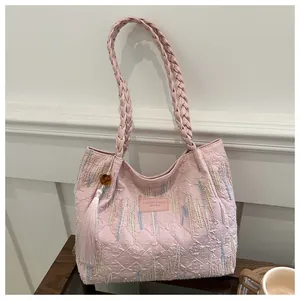 Dettaglio della borsa rosa con texture a rilievo, manico intrecciato e nappa decorativa