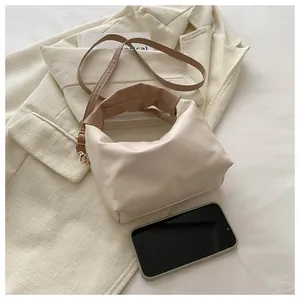 Detail of soft cream leather handbag with brown handles and adjustable shoulder strap