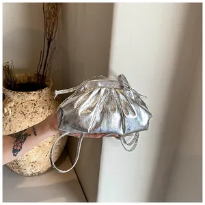 Detailed view of a silver metallic pleated dumpling bag with a thin crossbody strap.
