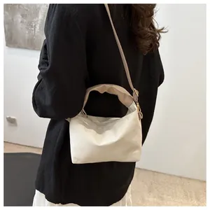 Detail of white pleated small square bag with beige scrunchie handle and gold hardware