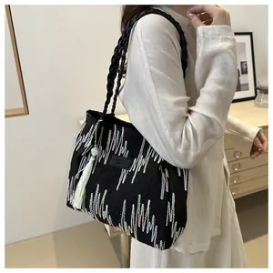 Dettaglio della borsa tote nera con ricami ondulati colorati e manici in pelle
