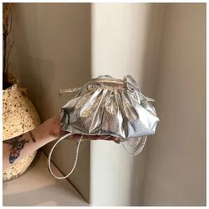 Detailed view of a silver metallic pleated pouch bag with a slim shoulder strap