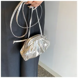 Close-up of metallic silver pleated dumpling bag featuring a minimalist cord strap