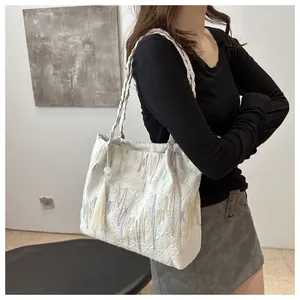 Dettaglio della borsa tote in jacquard bianco con ricami colorati e pendente a nappa