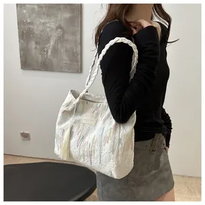 Dettaglio borsa tote in jacquard bianco con ricami verticali e manico in corda intrecciata