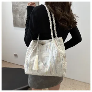 Dettaglio della borsa tote vintage con ricami floreali, nappe bianche e logo in pelle