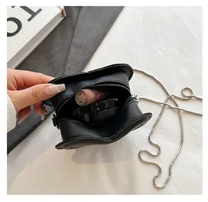 Detalle del interior del mini bolso de piel negra con forma de corazón y maquillaje