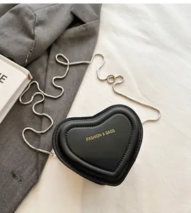 Detalle del bolso bandolera de cuero PU negro en forma de corazón con cadena plateada