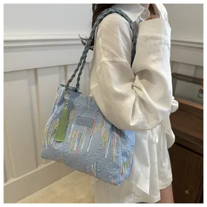 Dettaglio della borsa tote trapuntata celeste con ricamo colorato e ciondolo nappa verde