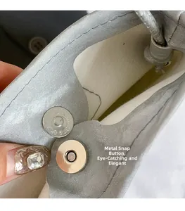 Close-up of the metal magnetic snap button on the grey faux suede crossbody phone bag