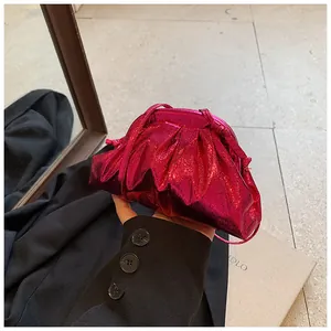 Detail of metallic rose red pleated dumpling bag with glossy finish and thin strap