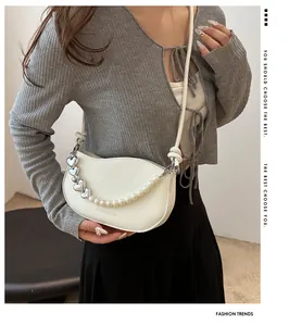 Close-up of white heart-shaped chain bag with pearls on a model in casual attire